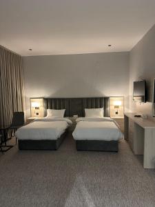 een hotelkamer met twee bedden en een televisie bij Bunyan Alula Hotel in Al Ula