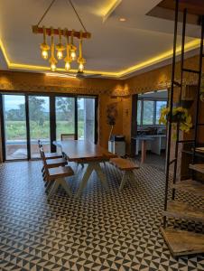 a dining room with a table and benches and windows at Aura Kabini by Tripture in Begūr