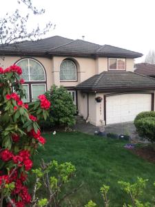 una casa con un garage e fiori rossi nel cortile di Warm house a Coquitlam
