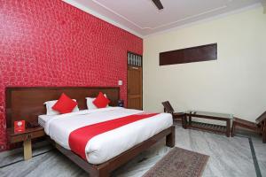 Un dormitorio con una cama y una pared roja. en Hotel O Shikhar Paradise, en Gomti Nagar