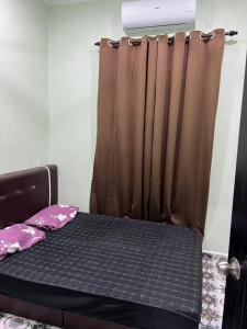 a bed with a brown curtain in a room at Inara Homestay in Kepala Batas