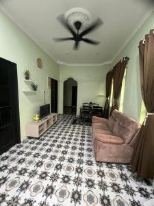 a living room with a couch and a ceiling fan at Inara Homestay in Kepala Batas