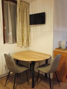 una mesa de madera con 2 sillas y una ventana en L'Epicéa - Logement Nature, en Mijoux 8 fotos más