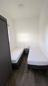 two beds in a room with white walls and wooden floors at Maison du Lac in Lathum