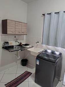 una piccola cucina bianca con lavandino e lavandino e un lavandino di Doce lar a Serra