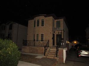 a large brick building with a porch at night at Cozy Rooms in Ozone Park in Brooklyn Manor
