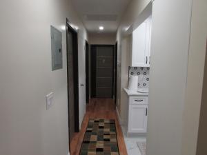 a hallway leading to a kitchen with a checkerboard floor at Cozy Rooms in Ozone Park in Brooklyn Manor