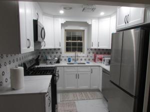 a kitchen with white cabinets and a stainless steel refrigerator at Cozy Rooms in Ozone Park in Brooklyn Manor +15 photos