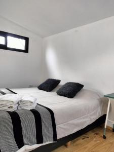 a bedroom with a bed with black and white pillows at Minicasas cerca del rio Los Reartes in Villa Ciudad Parque