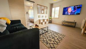 ein Wohnzimmer mit einer Couch und einem Fernseher an der Wand in der Unterkunft Maison familiale rénovée au calme a bon encontre in Bon-Encontre