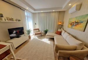 a living room with a white couch and a tv at 2 Bedroom Cozy Apartment in Antalya