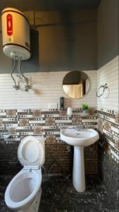 um banheiro com um vaso sanitário, uma pia e um espelho em Eleven 11 cafe and stay em Jibhi mais 12 fotografias