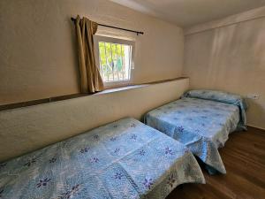 two beds in a small room with a window at La Mocha Casa Rural - La Casa de María in La Iruela