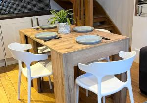 a wooden table with white chairs and plates on it at Talbot Lane Cottage Horsham By My Getaways in Horsham