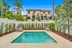 ein Swimmingpool mit zwei Stühlen und einem Haus in der Unterkunft New 4BR w Pool Walk to Las Olas 5mins to Beach in Fort Lauderdale