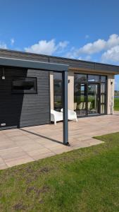a black building with a white bench on a patio at Maison du Lac in Lathum +6 photos