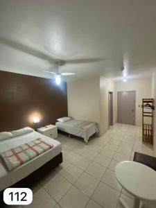 a hotel room with two beds and a table at Hotel Guaporé - Campo Bom RS in Campo Bom