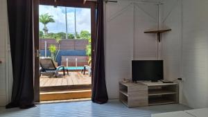 Location saisonnière في بيتي-بور: غرفة معيشة مع باب زجاجي منزلق مع تلفزيون