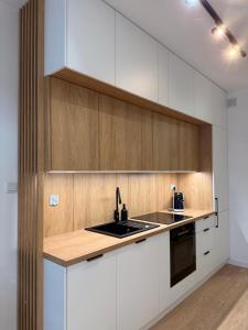 una cucina con mobili bianchi e un lavandino di Old Town Bulwar Apartment a Elblag