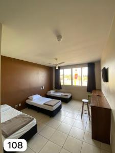 a hotel room with two beds and a table at Hotel Guaporé - Campo Bom RS in Campo Bom