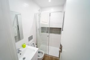a white bathroom with a shower and a sink at GREEN STUDIO - Apt 003 Aconchegante e Moderno in Tarrafal +10 photos