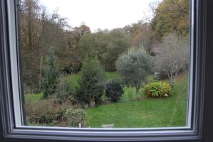 a window view of a garden with trees and bushes at Chambre d'hôtes cosy à la campagne in Bourg-des-Comptes