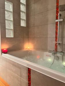 a bath tub with a red candle in a bathroom at Chambre d'hôtes cosy à la campagne in Bourg-des-Comptes +3 photos