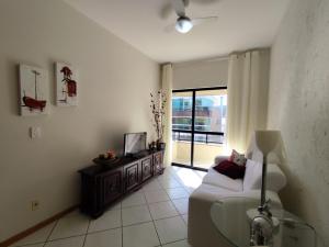 una sala de estar con un sofá y un televisor en B362 - Cobertura a poucos passos do mar com piscina privativa., en Bombas