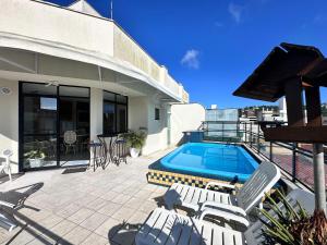 una casa y un patio con piscina y sillas en B362 - Cobertura a poucos passos do mar com piscina privativa., en Bombas