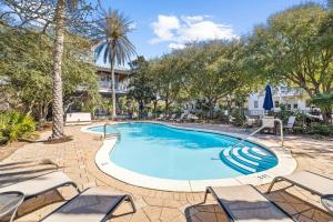 a swimming pool with lounge chairs and trees at Soakin it Up in Inlet Beach