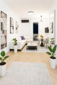 ポドゴリツァにあるWhite Lounge Haustorの白いソファと植物のあるリビングルーム