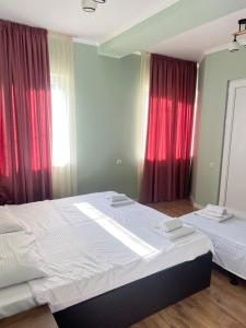 a bedroom with two beds and red curtains at Hotel maisis ezo in Kutaisi