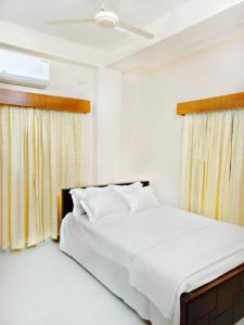 a bedroom with a bed with white sheets and a window at Best Eastern Apartments - With Balcony & Kitchen in Dhaka