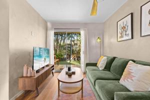 a living room with a green couch and a table at Casa Aloha Designer Condo w Oceanfront Pool in Kailua-Kona
