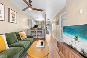 a living room with a green couch and a large flat screen tv at Casa Aloha Designer Condo w Oceanfront Pool in Kailua-Kona