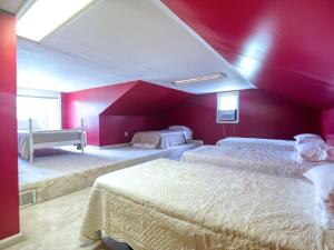 ein Schlafzimmer mit zwei Betten und einer roten Wand in der Unterkunft Boho Waterfront Getaway 5 Bedroom Retreat in Solomons