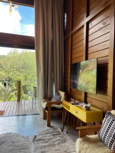 a living room with a tv and a yellow table at Sítio Rancho Mineiro in Domingos Martins