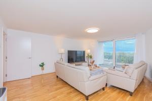ein Wohnzimmer mit 2 weißen Sofas und einem TV in der Unterkunft Modern High-Floor 3BR with Terrace & Thames View in Kew Bridge