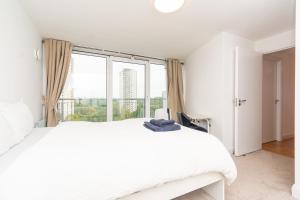 ein Schlafzimmer mit einem weißen Bett und einem großen Fenster in der Unterkunft Modern High-Floor 3BR with Terrace & Thames View in Kew Bridge