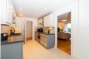 eine Küche mit weißen Schränken und ein Wohnzimmer in der Unterkunft Modern High-Floor 3BR with Terrace & Thames View in Kew Bridge