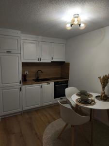 eine Küche mit weißen Schränken und einem Tisch und einer Spüle in der Unterkunft Apartment Panorama in Eischoll