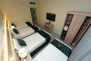 a hotel room with two beds and a television at Rose Holiday i3 روز هوليداي in Medina