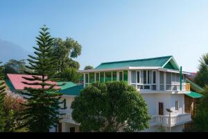 a large white house with a green roof at Brookfield in Pālampur