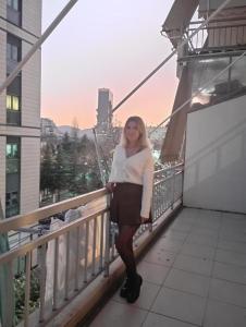 a woman standing on a balcony of a building at ROYAL Hostel in Tirana