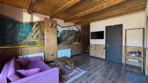 a living room with a purple couch and a painting at Checkin Kazbegi in Stepantsminda