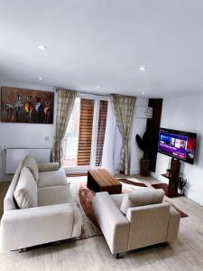 a living room with two white couches and a flat screen tv at Luxury 2-Bedroom London Apartment, 25mins to Liverpool Street, Balcony, Free Parking in London