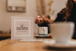 a sign on a table next to a cup of coffee at Hotel Catalunya Ribes de Freser in Ribes de Freser