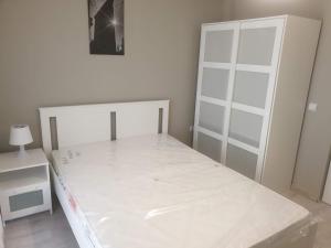 a white bedroom with a bed and a white cabinet at MCD Apartment Central in Craiova