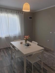 a white table with chairs and a vase of flowers on it at MCD Apartment Central in Craiova