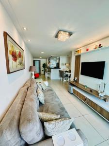 a living room with a large couch and a flat screen tv at Resort Praia Grande in Arraial do Cabo